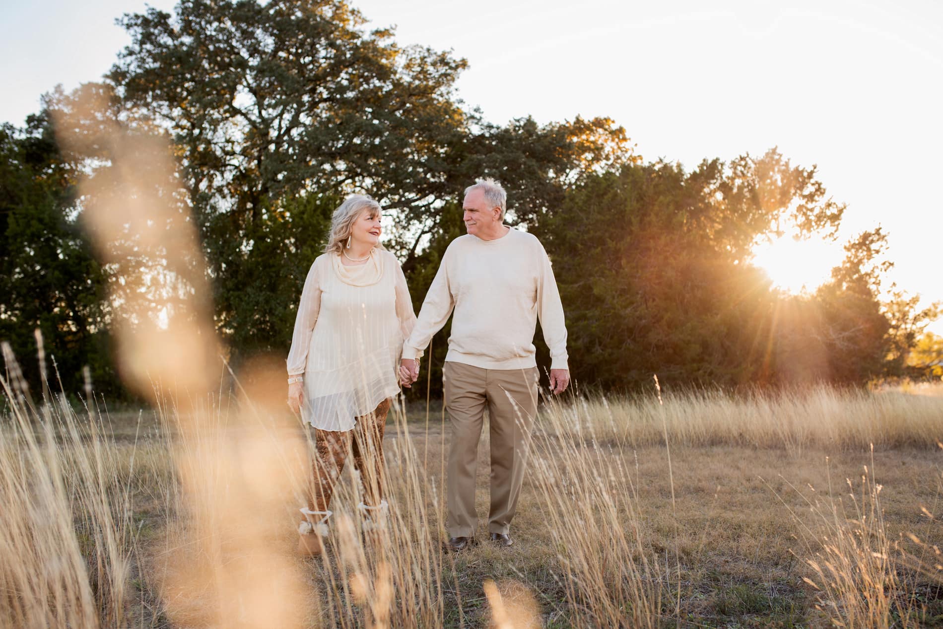 Family Photographer, elderly couple walk hand in hand through dry grass