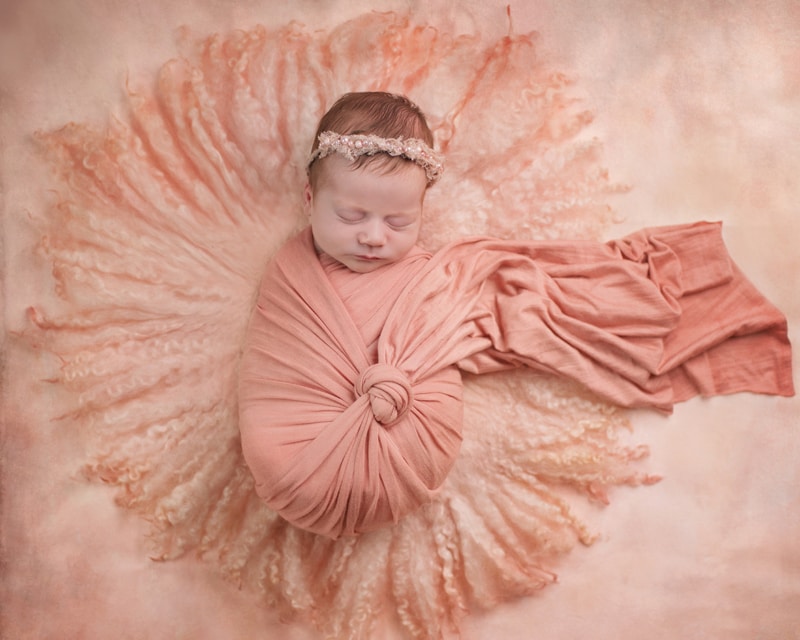 Newborn Photography, baby lay sleeping swaddled in linens and on a cushion