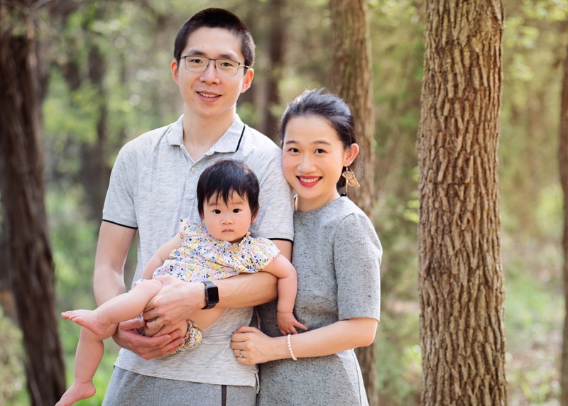 milestone photography, mother and father hold their daughter in the forest