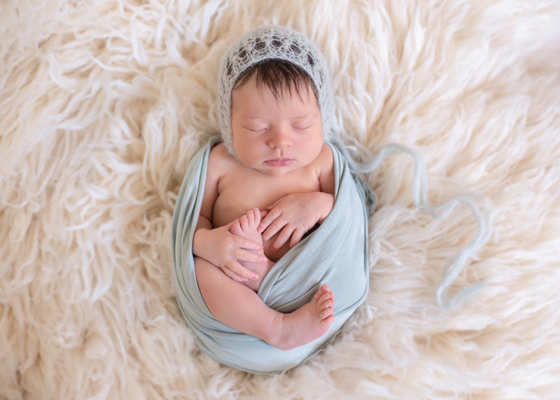 Newborn Photography,  a little baby sleeps wearing a beanie