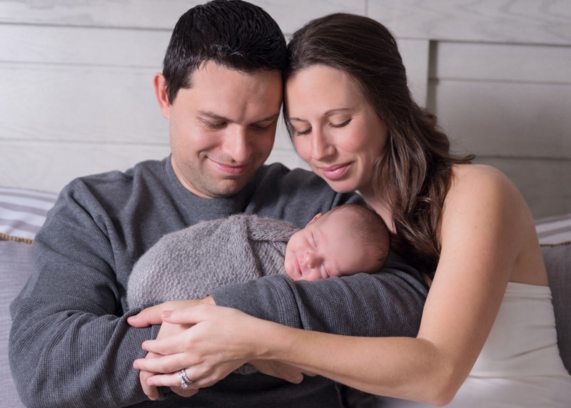 Newborn Photography, a husband and wife hold their newborn baby at home