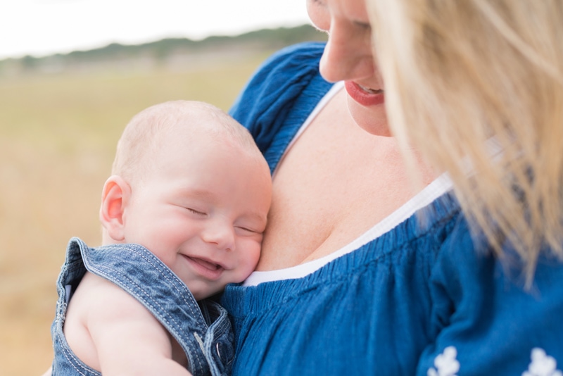 milestone photography,  mom holds smiling baby near her chest