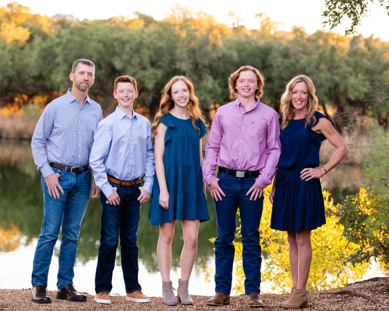 Family Photographer, Family of five stand happy before a quiet river near forest