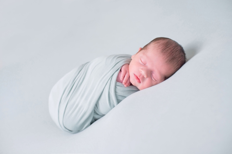 Newborn Photography, A baby lays sleeping wrapped in linens
