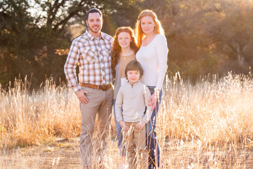Newborn and maternity photographer, Kelli is with her family in a dry meadow