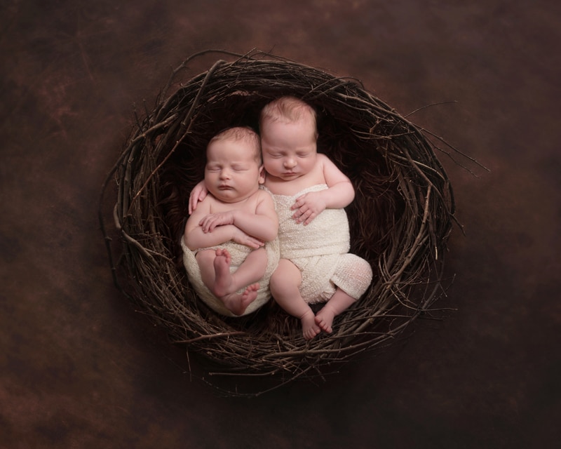 Newborn Photography, twins sit laying happy in a little nest basket